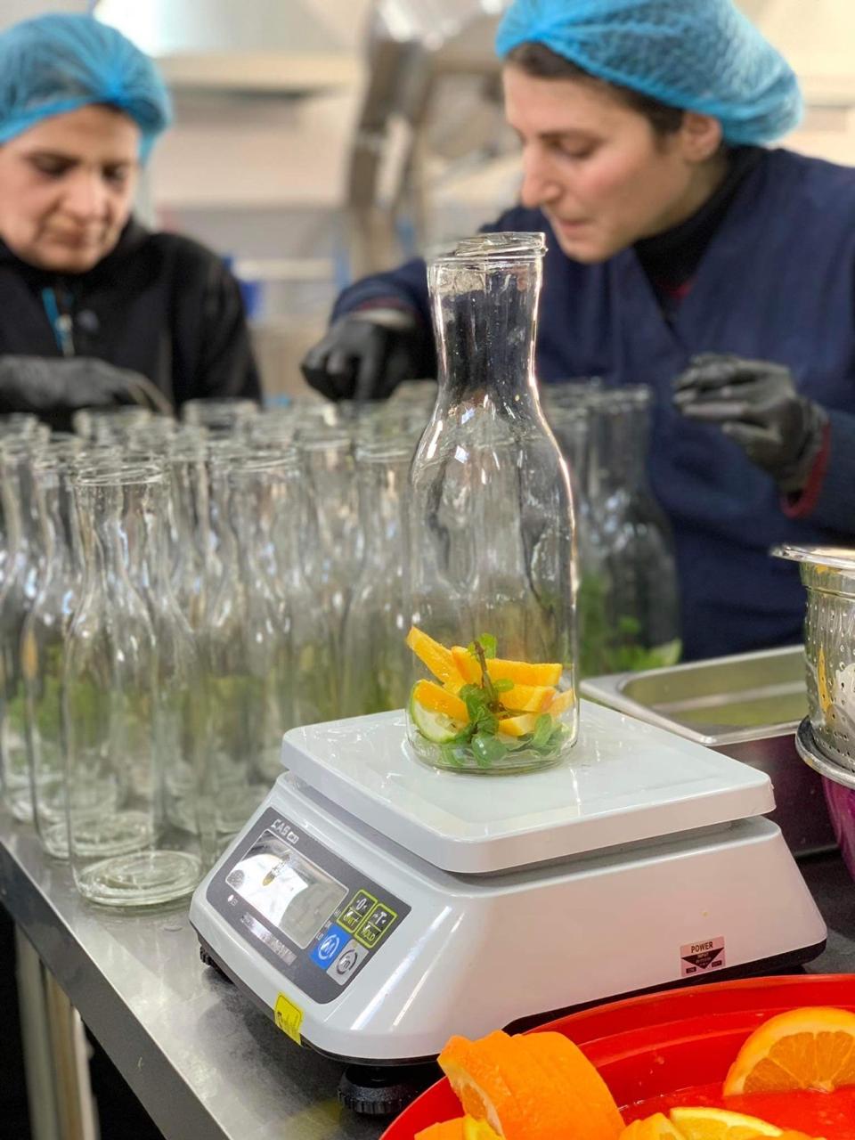 Operators weighing fresh fruit into bottles